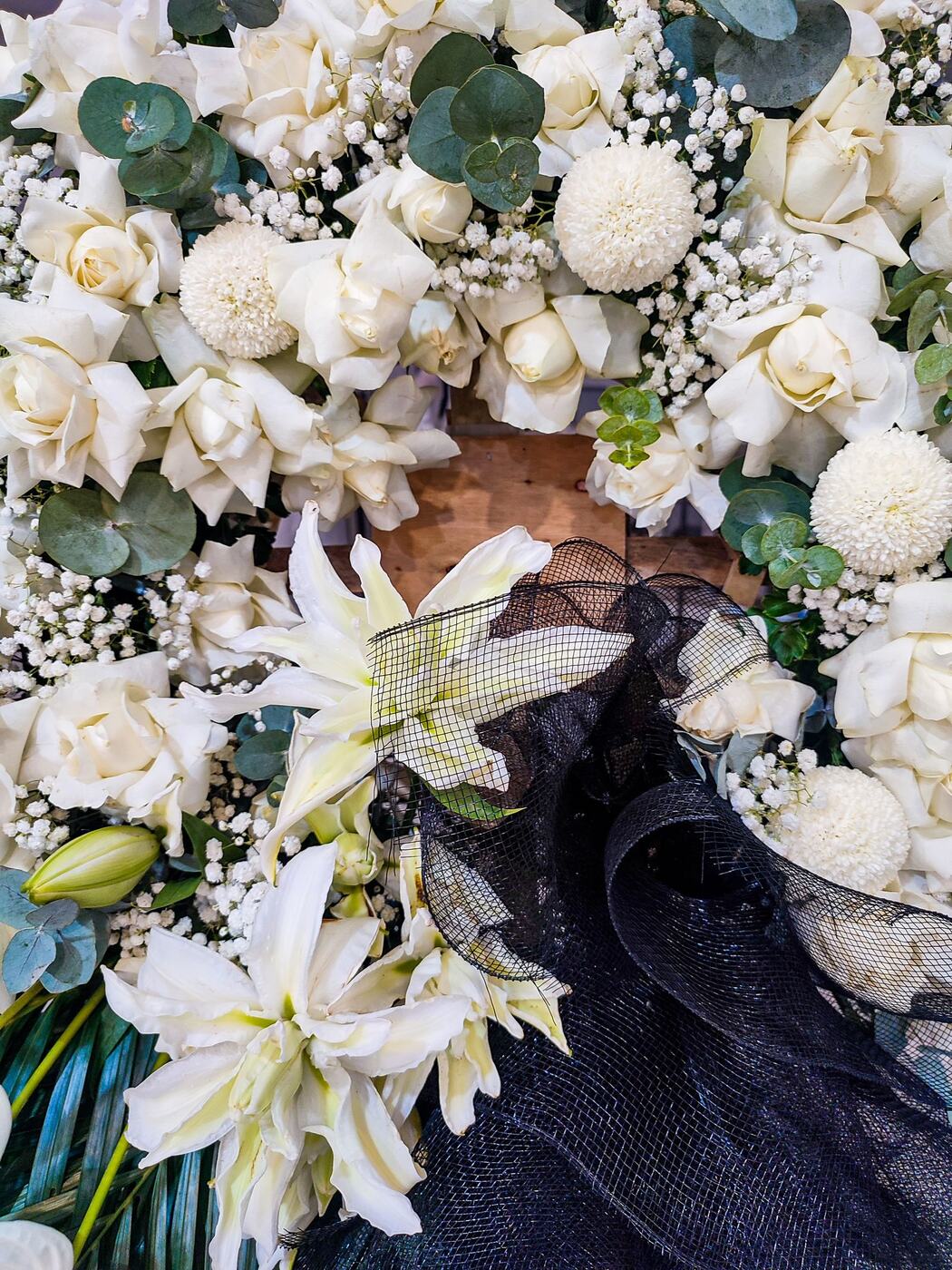 White roses, lilies and mums with eucalyptus in a sympathy arrangement